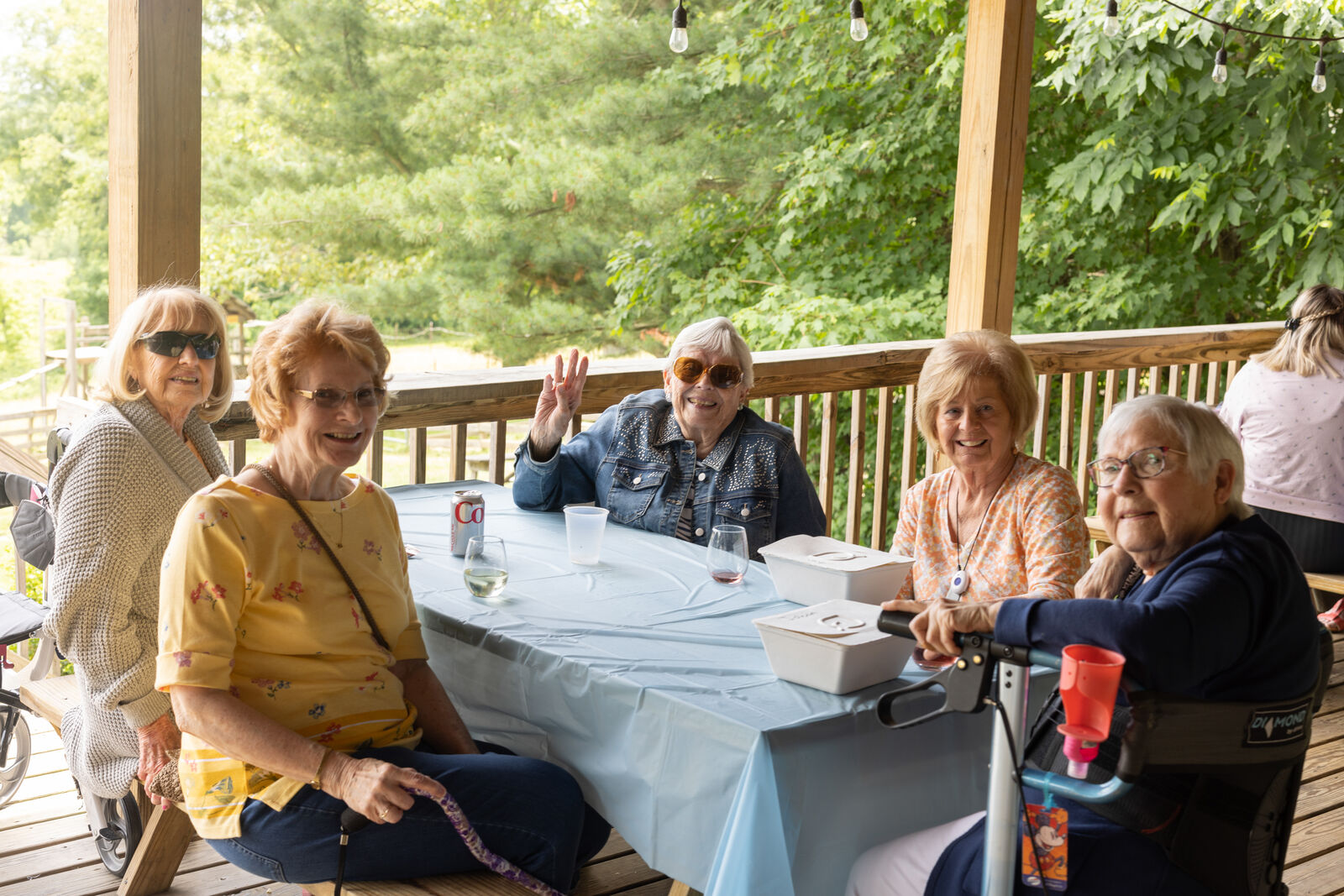 Group of seniors on a trip to a winery sitting at a table smiling and waving