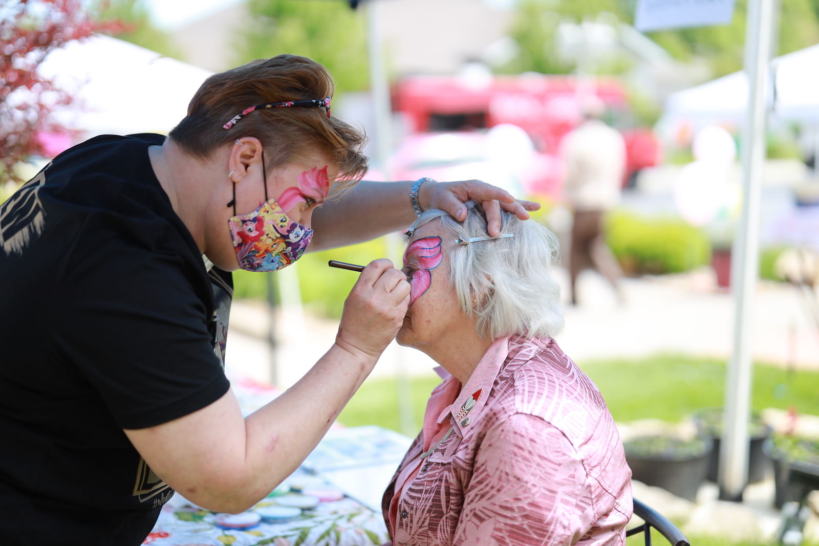 Senior woman at a celebration at her senior living community getting her face painted