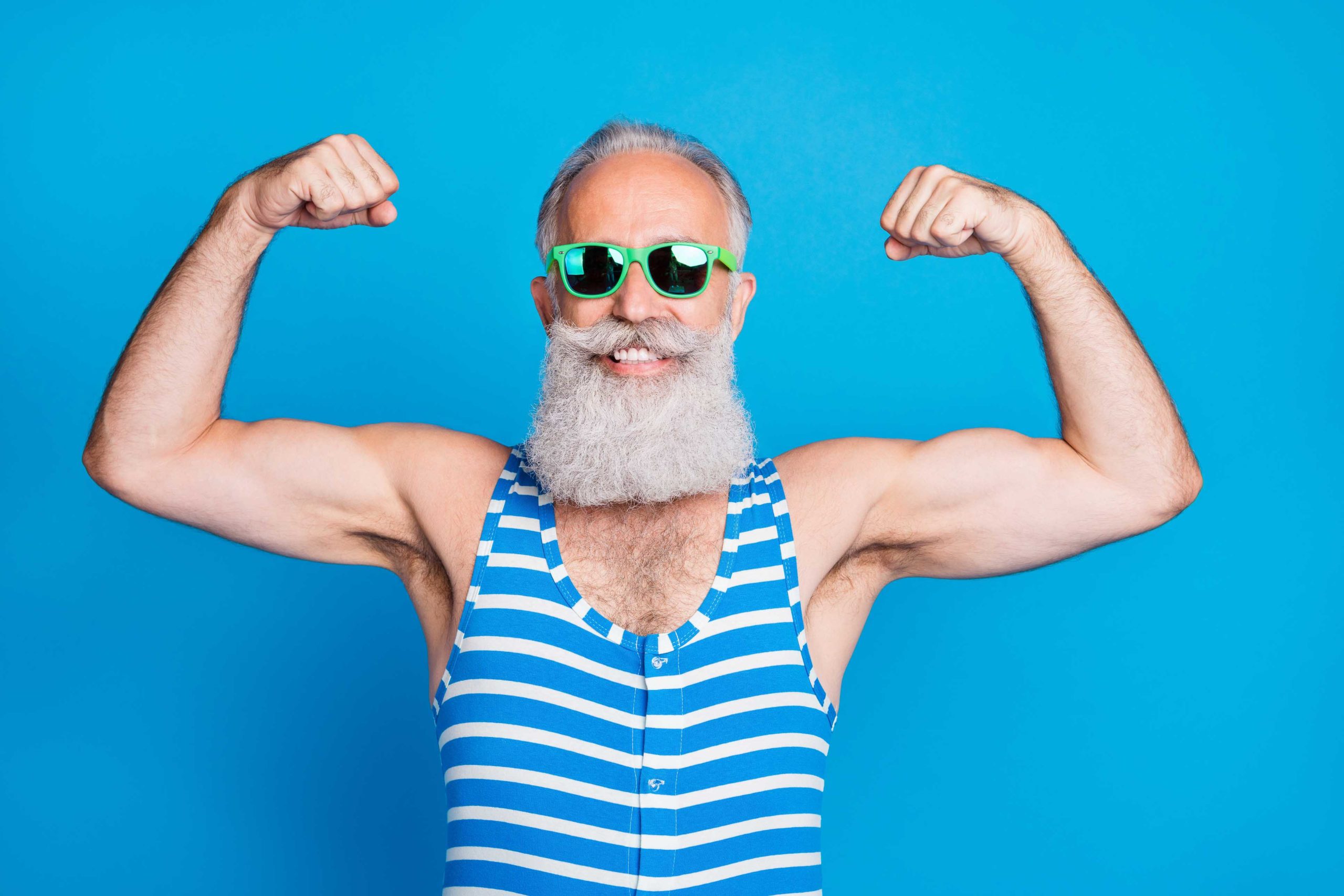 Fit senior man wearing goggles and a swimsuit flexing his muscles to represent strength and healthy physical aging